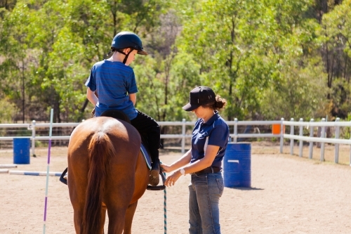 Riding instructor teaching young rider how to ride horse - Australian Stock Image