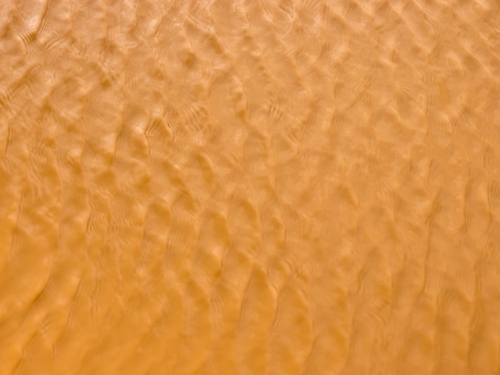 Ripple pattern on orange/brown muddy water - Australian Stock Image