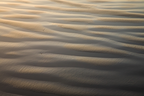 Ripple patterns of sand and water on a beach - Australian Stock Image