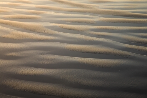 Ripple patterns of sand and water on a beach