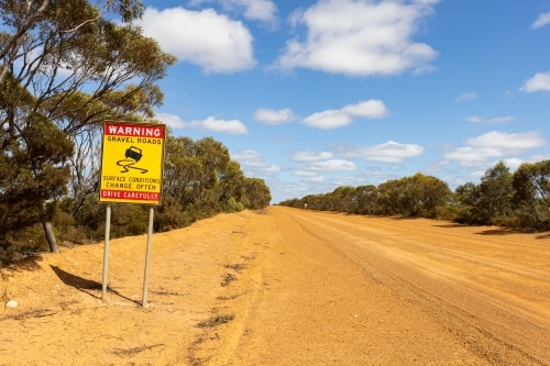 road sign warning of gravel road and changing conditions