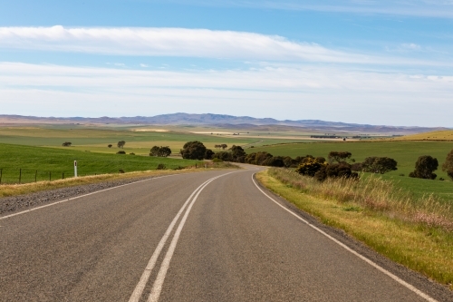 road winding through green farm land - Australian Stock Image
