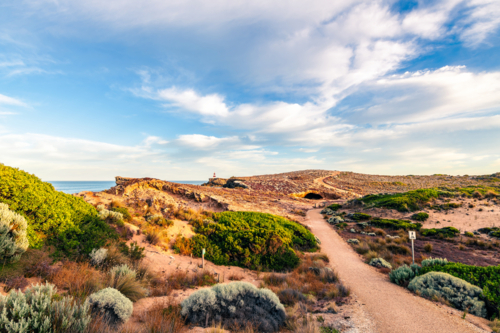 Robe Coastal Walk with the Obelisk viewed along the rugged Limestone Coast with the ocean during sun - Australian Stock Image