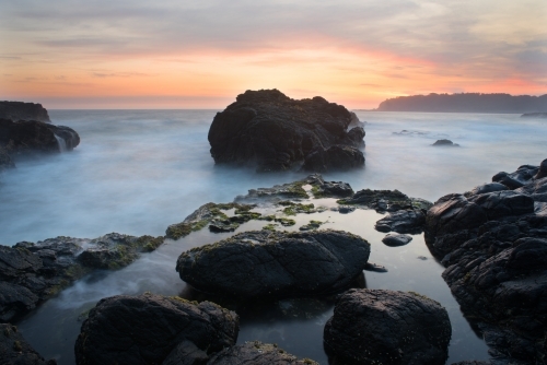 Rock in the ocean taken at dawn taken with long exposure - Australian Stock Image