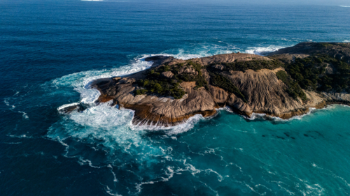 Rocky coastal island surrounded by turquoise waters - Australian Stock Image
