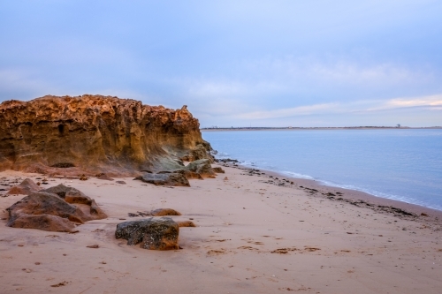 Rocky coastline and beach beneath cloudy sky - Australian Stock Image