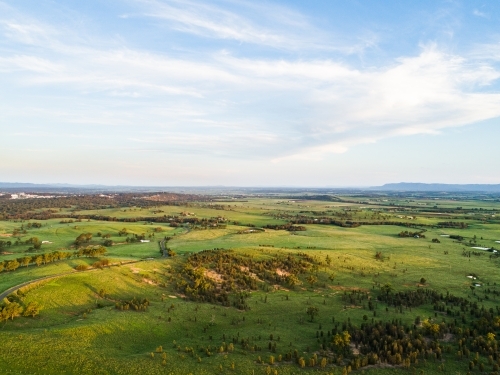 Rolling hills and green farm paddocks at dusk growing after rain - Australian Stock Image