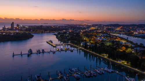 Rows of yachts and boats moored along illuminated piers at dusk - Australian Stock Image