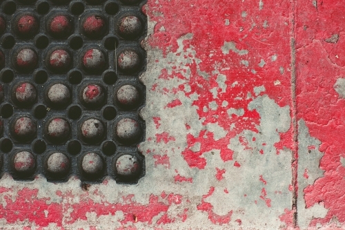 rubber mat on concrete with red flaking paint - Australian Stock Image