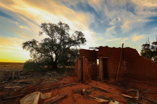 Ruins of abandoned mud brick home on rural property at sunset - Australian Stock Image