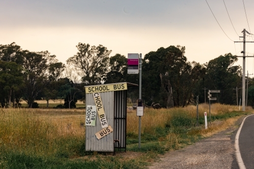 Rural bus stop on the roadside in country Victoria covered in signs - Australian Stock Image