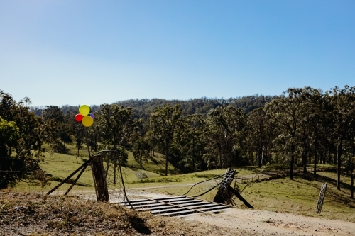 Rural country gateway with cattle grid and balloons tied up for birthday