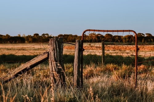 Rural country scene with rusty farm gate leading to dry paddock - Australian Stock Image