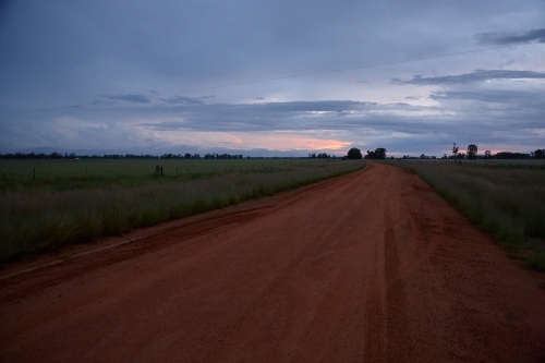 Rural dirt road and surrounding farmland on sunset - Australian Stock Image