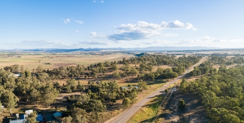 Rural road past paddocks and cliff to distant farmland - Australian Stock Image