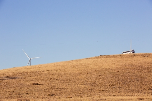 Rural Wind Turbines in a farm setting with bus on hilltop