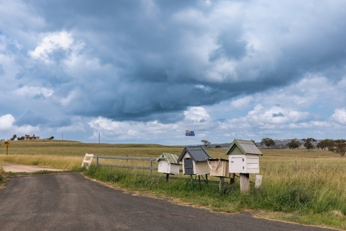 Rustic roadside mailboxes in remote area of country New South Wales with Australian flag flying - Australian Stock Image