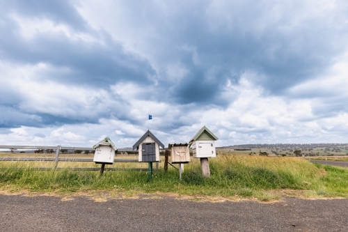 Rustic roadside mailboxes in remote area of country New South Wales with Australian flag flying - Australian Stock Image