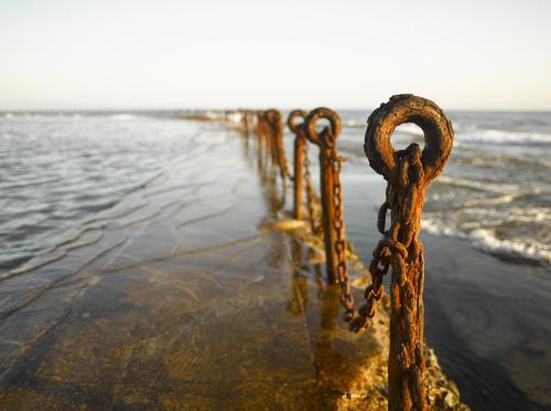 Rusting posts and chains along ocean pool - Australian Stock Image