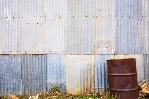 Rusty drum in front of corrugated iron wall - horizontal - Australian Stock Image