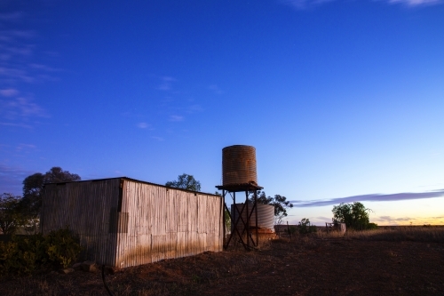 rusty old shed and tank at twilight - Australian Stock Image