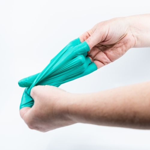 Safely removing green surgical gloves - Australian Stock Image