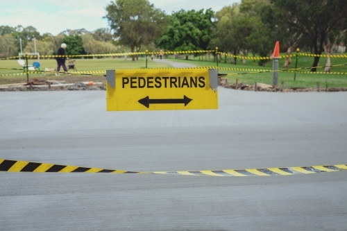 Safety black and yellow tape with pedestrians sign at the park - Australian Stock Image