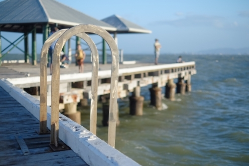 Safety ladder on a jetty with people on the background - Australian Stock Image
