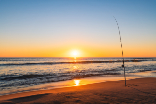 Salmon fishing off the beach at Port Noarlunga during sunset, South Australia - Australian Stock Image