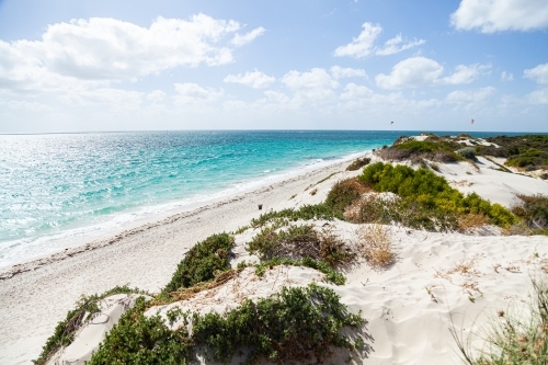 Sand dunes and beach with kitesurfing people in the distance - Australian Stock Image
