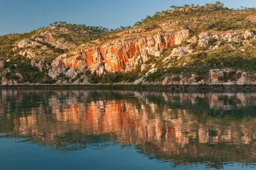 Sandstone cliffs reflected in calm water