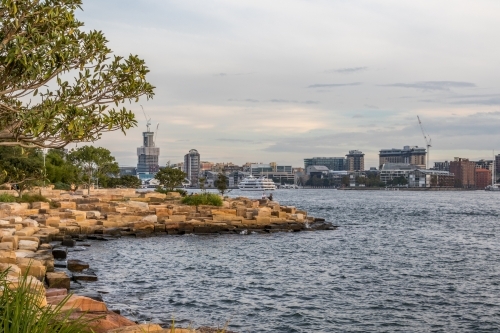 Sandstone lined coastline against ocean city skyline - Australian Stock Image