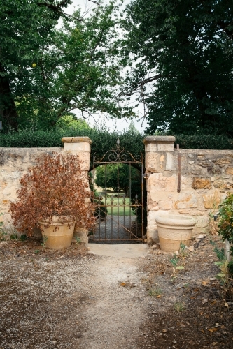 Sandstone wall with iron gate leading to green garden