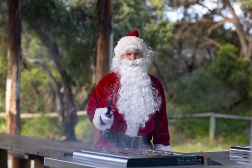 santa tending to the barbecue on an electric hotplate in a park - Australian Stock Image