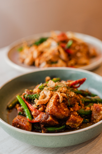 Savoury stir-fried chicken with green beans and red chili peppers served in a bowl - Australian Stock Image