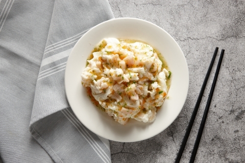 Scallop with egg white in a plate on a concrete surface with chopsticks - Australian Stock Image