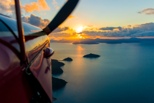 Scenic aerial view at sunset from a small aircraft over island-dotted ocean. - Australian Stock Image