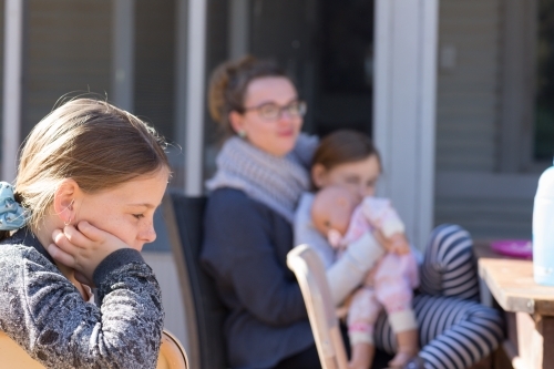 School-aged child with woman and younger child in background - Australian Stock Image