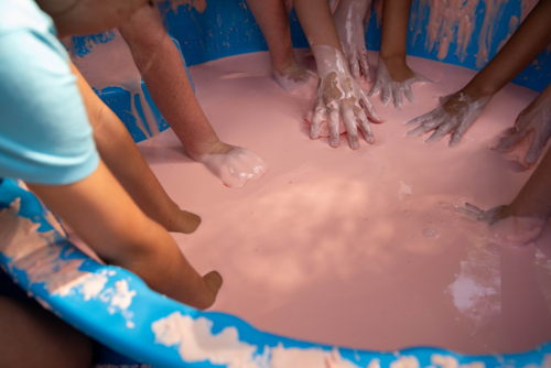 Science experiment with children dipping hands into oobleck, cornstarch and water mixture - Australian Stock Image