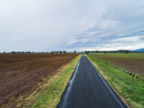 Sealed country road through brown ploughed farmland - Australian Stock Image