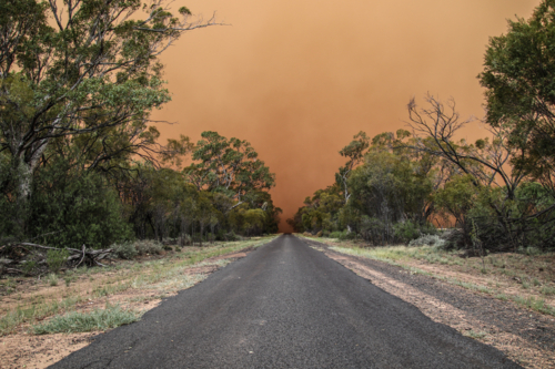 Sealed road stretching into the distance with dust cloud storm in the sky - Australian Stock Image