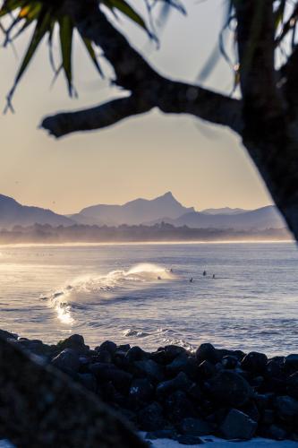Seascape of surfers and rocks at sunset in Byron Bay - Australian Stock Image