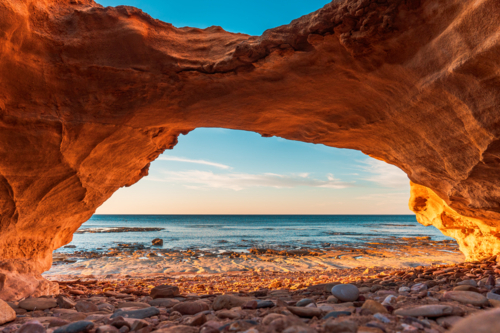 Secluded Beach View Through a Sandstone Sea Cave - Australian Stock Image