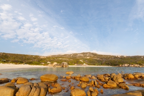 secluded white sand beach with rocks in foreground - Australian Stock Image