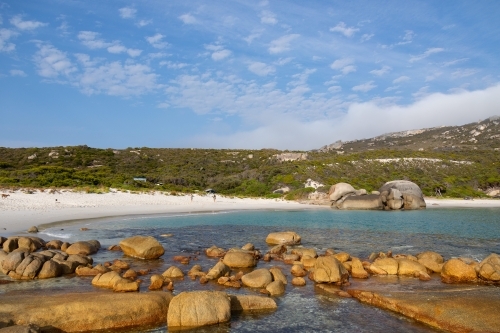 secluded white sand beach with rocks in foreground - Australian Stock Image
