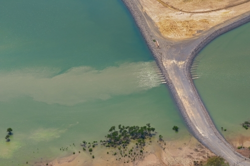 Sediment flow from pipes between the sea and a sedimentation deposit pond, Fisherman's landing - Australian Stock Image