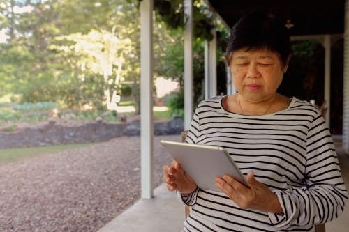 Senior Asian woman using tablet - Australian Stock Image