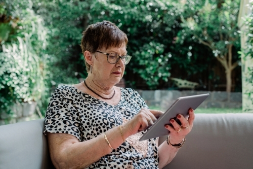 Senior lady sitting in garden browsing social media