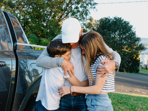 Senior man embracing his grandchildren outside the house. - Australian Stock Image