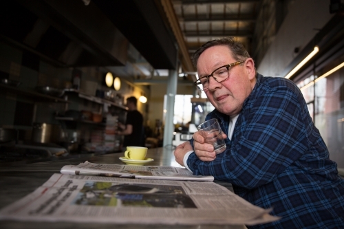 Senior Man Reading Newspaper in Coffee Shop - Australian Stock Image